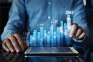 Man at a tablet that is projecting bar graph with the dates 1990, 2005, 2020, and 2025