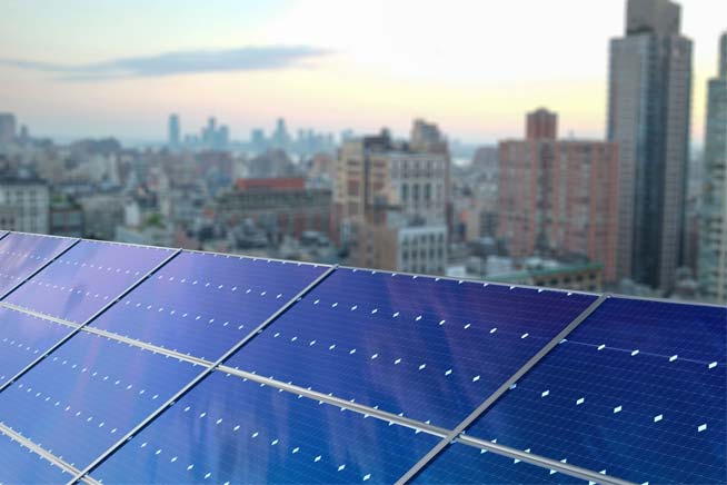 Close up of solar panel and city skyline in distance Close up of solar panel and city skyline in distance