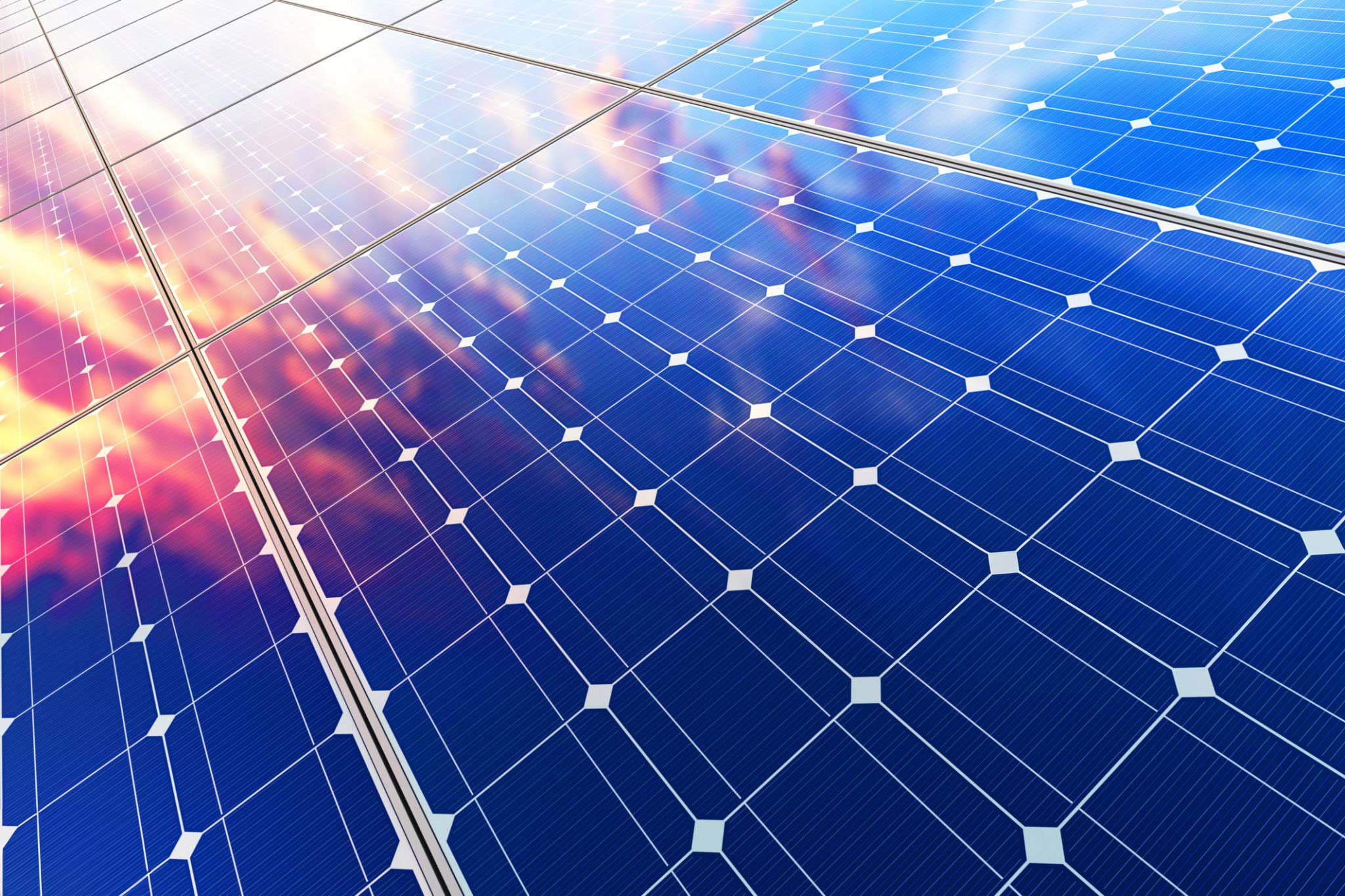 Up close view of solar panels and reflection of reds and orange from sunset